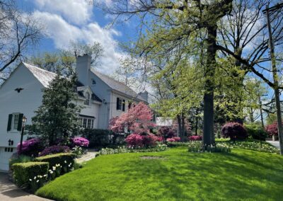 A white house with green grass and flowers.