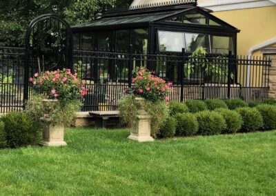 A black wrought iron fence and flower pots in front of a house.