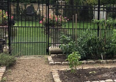 A garden with an iron gate and some plants.