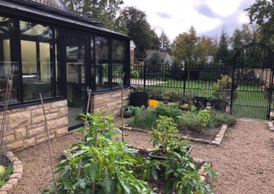 A garden in a backyard with a greenhouse.