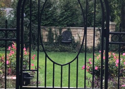 A black wrought iron gate in a garden.