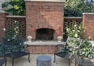 A patio with a brick fireplace and chairs.