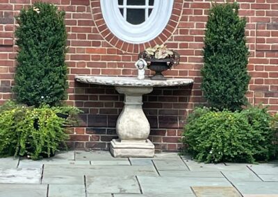 A brick wall with a fountain in front of it.