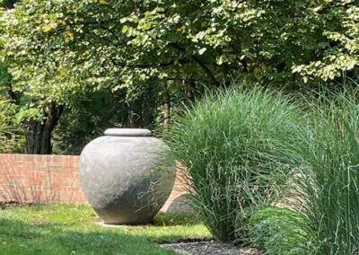 A stone urn sits in the middle of a grassy area.